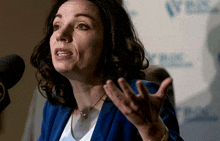 a woman in a blue jacket speaks into a microphone in front of a sign that says nbc