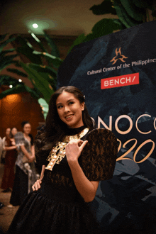 a woman in a black dress stands in front of a sign that says cultural center of the philippines