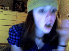 a woman wearing a blue plaid shirt and a beanie has a gif run.com watermark on the bottom