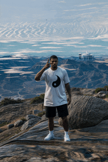 a man wearing a white t-shirt with a black yin yang symbol on it