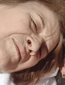 a close up of a woman 's face with her eyes closed and a white towel around her neck