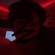 a close up of a person 's face in a dark room with red lights behind them .