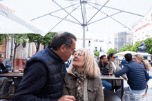 a man and woman are sitting under an umbrella that says ' mahou ' on the top