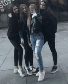 a group of young women standing next to each other on a sidewalk .