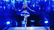 a woman in a blue and white outfit is dancing on a stage in front of a blue background .