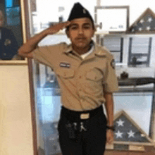 a young man in a military uniform salutes in front of a picture of a man in a military uniform .