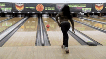 a woman is playing bowling in a bowling alley with a sign that says " you still have one hand free "