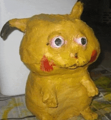 a statue of a yellow animal with big eyes and red spots on its face