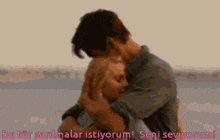 a man is holding a woman in his arms with the words " seni seviyorum " written below him