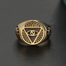 a gold ring with an eye in a triangle