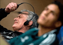 a man is wearing headphones while another man is laying down