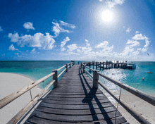 a wooden pier leads to the ocean with a boat in the distance