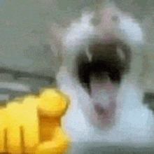 a blurry picture of a cat with its mouth open and a yellow fist pointing at it .