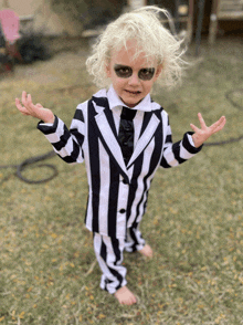 a little boy in a black and white striped suit