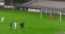 a group of soccer players are playing a game on a field with a coca cola banner in the background .