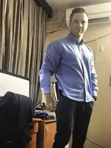 a man in a blue shirt is standing in front of a desk