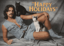 a man laying on a bed with two cats and the words happy holidays behind him