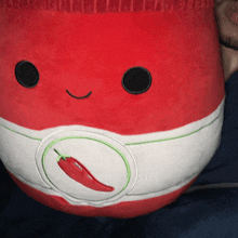 a red and white stuffed animal with a red pepper embroidered on its belly