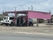 a white van is parked under a pink structure