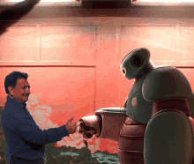 a man is shaking hands with a robot in front of a red wall