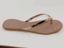 a pair of flip flops with a gold strap on a white background