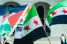 a man wearing a free syria shirt holds a flag