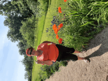 a woman in an orange shirt is standing in a garden