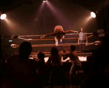 a man is doing a handstand in a wrestling ring while a referee looks on