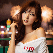 a woman wearing a toto macau t-shirt looks at the camera