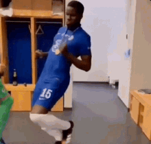 a soccer player is dancing in a locker room while wearing a blue jersey with the number 15 on it .