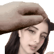 a hand is touching a woman 's forehead with a hat on .