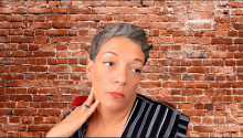 a woman in front of a brick wall has a ring on her finger