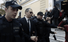 a man in a suit and tie is being escorted by police officers