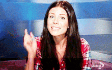 a woman in a plaid shirt is sitting in front of a blue wall with the word global on it