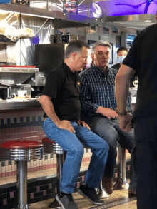 two men sit on a stool in a diner