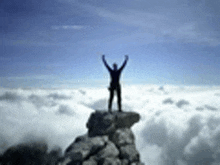 a man is standing on top of a mountain with his arms outstretched .