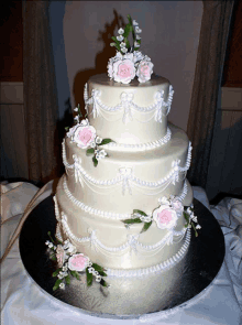 a three tiered wedding cake with pink roses on top