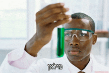 a man in a lab coat looking at a green liquid