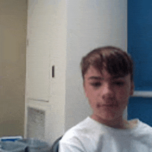 a young boy in a white shirt is sitting in a chair in a room .