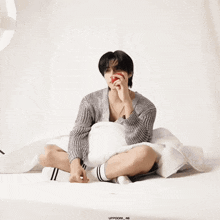 a man is sitting on a bed eating an apple and has the number 66 on the bottom right