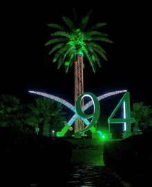 a palm tree is lit up with green lights and the number 94 is lit up in green