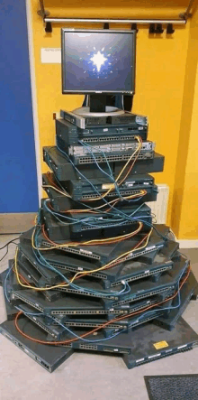 a computer monitor sits on top of a stack of cisco equipment