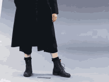 a person wearing a black coat and black boots