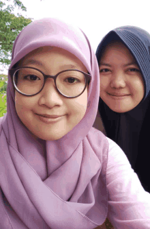 a woman wearing glasses and a purple scarf poses for a picture with another woman