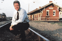 a man is squatting on train tracks in front of a hope station