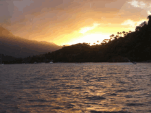 a sunset over a body of water with mountains in the distance