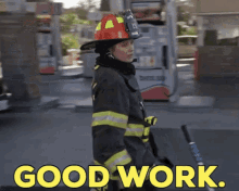 a woman in a fireman 's uniform is standing in front of a gas station with the words good work written in yellow