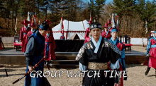 a group of men in ancient costume are standing in a field with the words group watch time below them