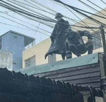 a man is standing on top of a building surrounded by power lines .