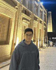 a man wearing a hoodie that says northland stands in front of a brick building